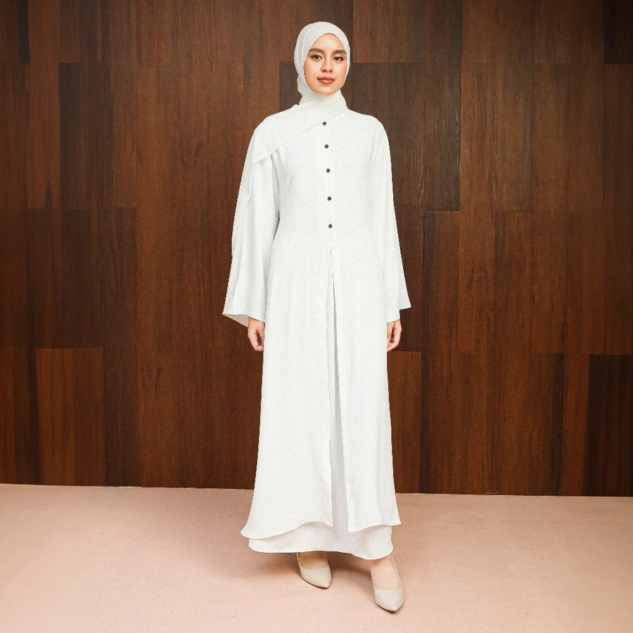 Woman wearing a broken white abaya dress by Lozy Hijab with a hijab against a wooden background