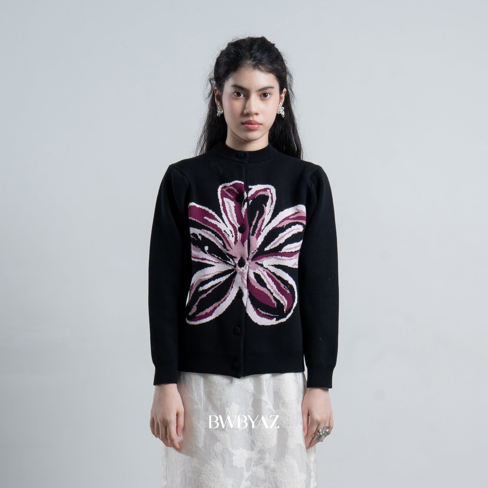 Woman wearing a black cardigan by BWBYAZ with a floral design on a plain background