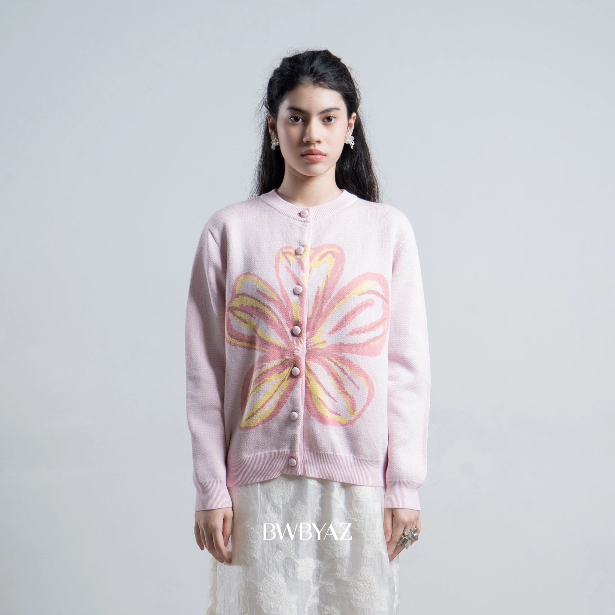 Person wearing a pink cardigan by BWBYAZ with a floral design on a plain background