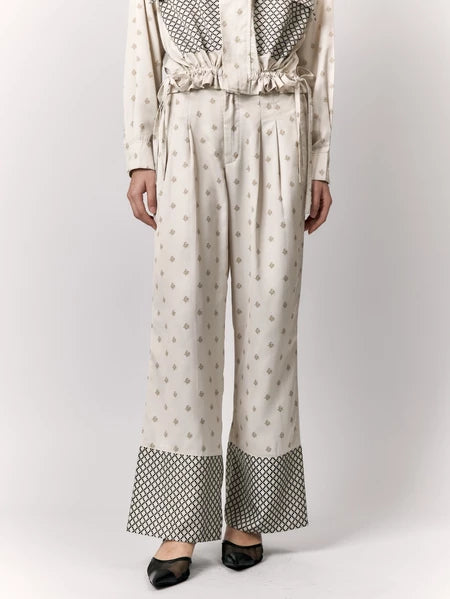 Person wearing a cream-colored outfit with patterned pants by Studio Tui on a white background