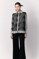 Person wearing a patterned shirt by Studio Tui with black pants on a white background