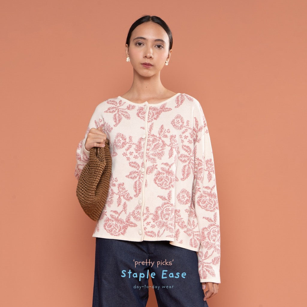 Woman wearing a pink floral cardigan by BWBYAZ against a peach background.