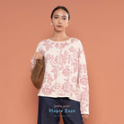 Woman wearing a pink floral cardigan by BWBYAZ against a peach background.