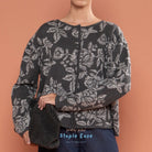 Person wearing a dark floral-patterned cardigan by BWBYAZ against a brown background