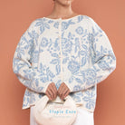 Person wearing a white cardigan by BWBYAZ with blue floral pattern against a peach background