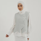Woman wearing a light gray textured vest by Tunique over a white shirt on a plain background
