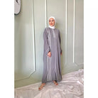 A person wearing a gray dress by Abame with white vertical stripes, standing against a neutral background.