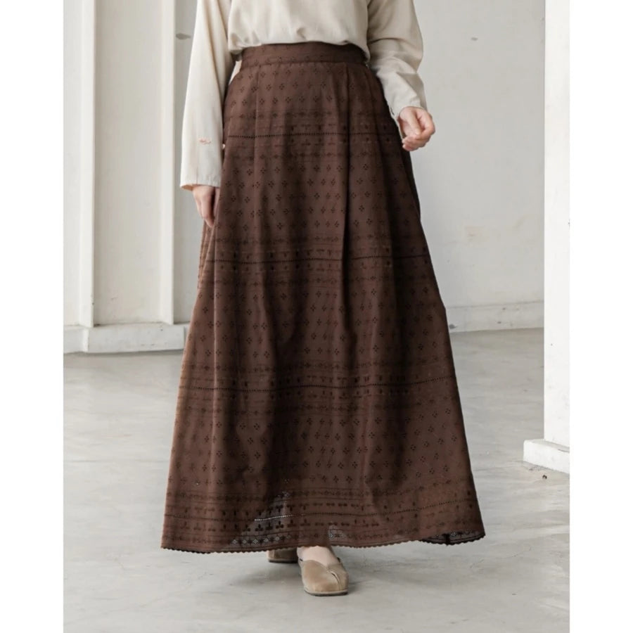 Person wearing a long brown patterned skirt by Mistyvori with a white top in a minimalistic setting