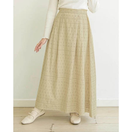 Person wearing a butter-colored patterned skirt by Mistyvori with a white top on a light wooden floor.