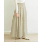 Person wearing a long khaky skirt by Mistyvori with a white top and shoes on a light wooden floor.