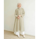 Seorang wanita menggunakan Aziza Tunik, tunik berbahan katun embriodery yang busui friendly, berwarna khaki dari brand Mistyvori.