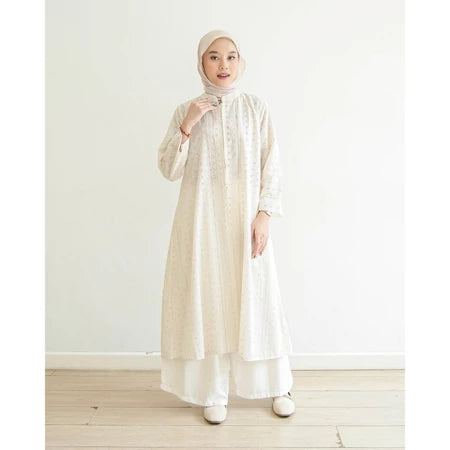 Seorang wanita menggunakan Aziza Tunik, tunik berbahan katun embriodery yang busui friendly, berwarna milky dari brand Mistyvori.