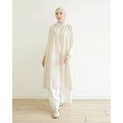 Woman wearing a long white vest by Mistyvori over white inner with a hijab against a white background