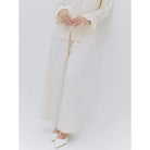 Person wearing a cream pants by Renaette with a plain background