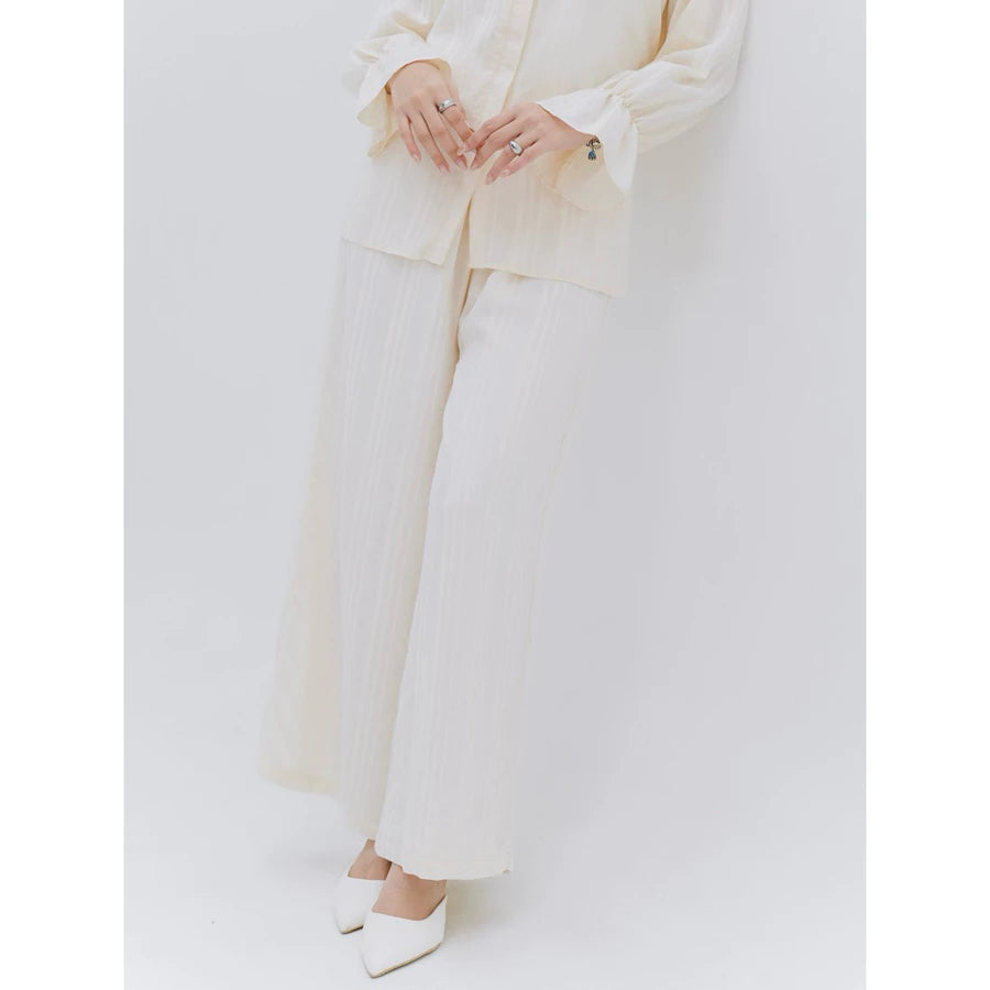 Person wearing a cream pants by Renaette with a plain background