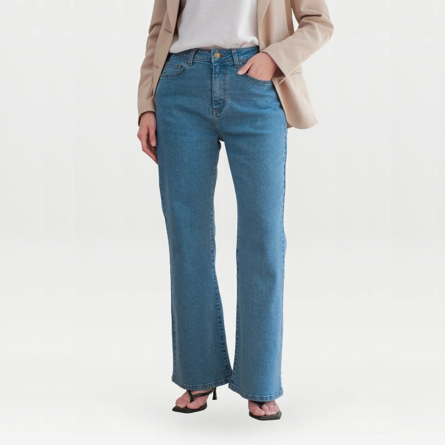 A model wearing a pair of medium-wash blue flare denim pants, styled with a beige blazer, white top, and black sandals against a plain white studio background.

Seorang model mengenakan celana denim flare berwarna biru dengan warna medium-wash, dipadukan dengan blazer krem, atasan putih, dan sandal hitam, dengan latar belakang studio berwarna putih polos.