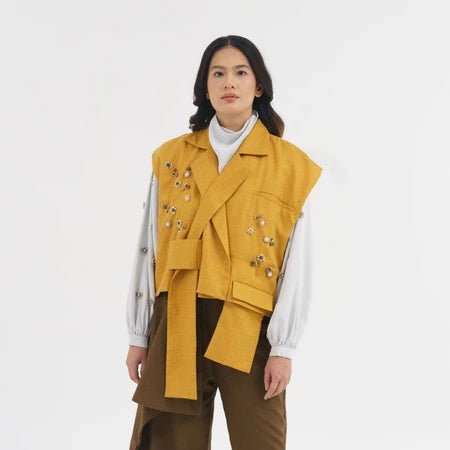 Person wearing a mustard yellow vest by Jenna & Kaia over a white shirt on a white background