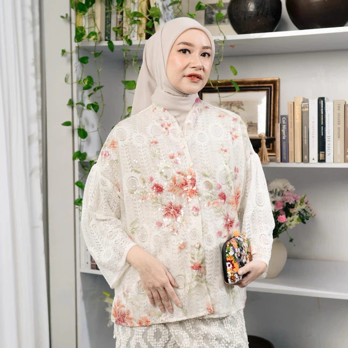 Woman wearing a floral blouse by Haidee Orlin with green accents in a room with shelves and plants