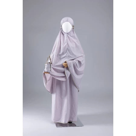 Mannequin wearing a light purple mukena for kids from Muhajir Project on a gray background