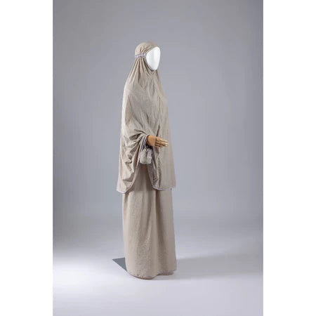 Beige mukena from Muhajir Project on a mannequin against a gray background