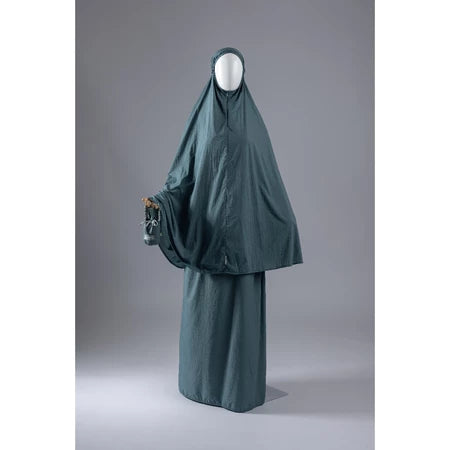 Dark green mukena from Muhajir Project on a mannequin against a gray background