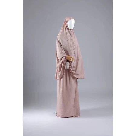 Light peach mukena from Muhajir Project on a mannequin against a gray background