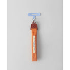 Orange keychain strap with a brown buckle from Muhajir Project on a gray background