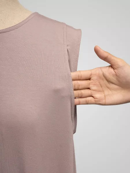 Light pink sleeveless top on a mannequin with a hand pointing to it, against a gray background