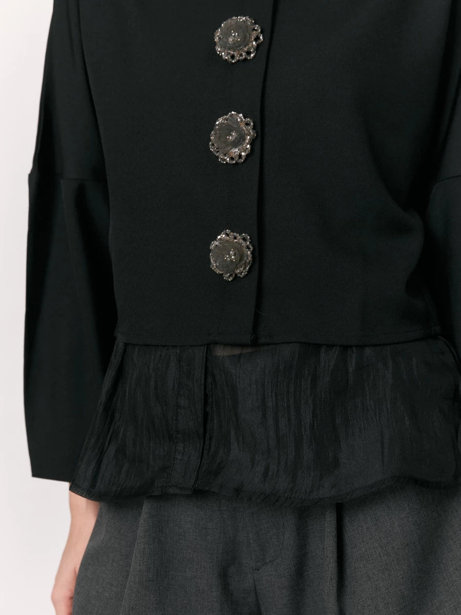 Black shirt with decorative buttons by Studio Tui on a white background