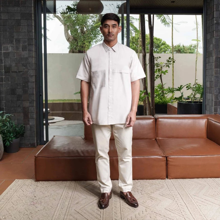 Man standing in a modern outdoor setting wearing beige shirt by Jenna & Kaia.