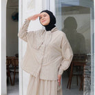 A woman standing outdoors wearing a beige shirt with long sleeves and a round neckline by Casa Elana, the shirt appears to be made of crinkle fabric.