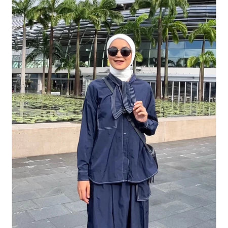 A woman standing outdoors wearing a navy shirt with long sleeves and a round neckline by Casa Elana, the shirt appears to be made of crinkle fabric.