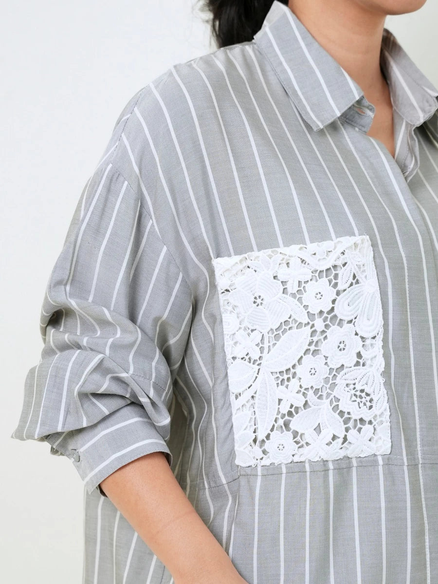 A close-up of a gray and white vertically striped button-up shirt by Studio Tui with a large white floral lace pocket on the chest, worn by a model.