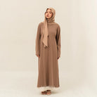 Woman wearing a light brown dress by BWBYAZ and hijab on a beige background