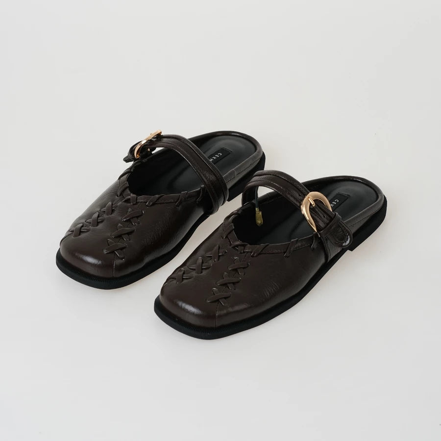 Pair of brown sandals by Cekhas with a strap on a light gray background