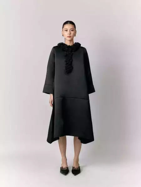 Woman wearing a black dress by Studio Tui with ruffled details on a white background