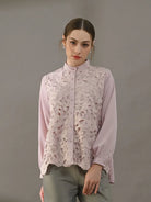 Woman wearing a light pink blouse with lace detailing by Kasa Heritage on a gray background