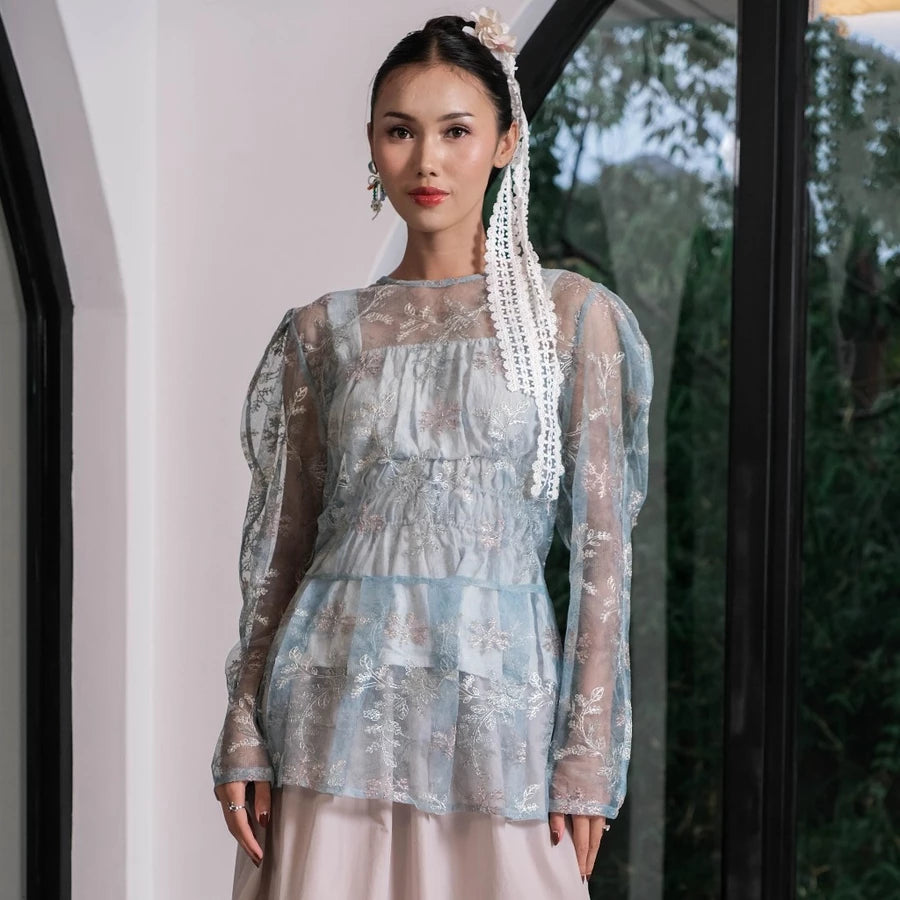 Woman wearing a light blue sheer floral outer by Holy Peony indoors.