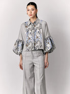 Woman wearing a gray outer by Studio Tui with floral cuffs and a matching skirt on a light gray background