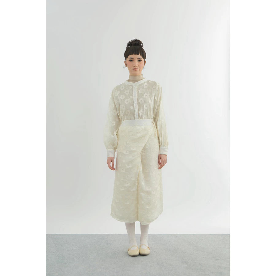 Person wearing a long, light-colored top and wrap skirt by Yestoday with a sheer overlay against a white background