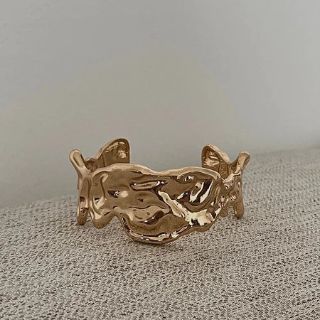Gold bracelet by Darje on a textured surface with a neutral background