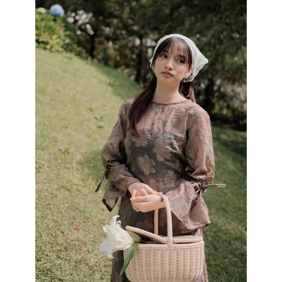 Woman in a ash brown top with floral embroidery by Renaette holding a basket outdoors