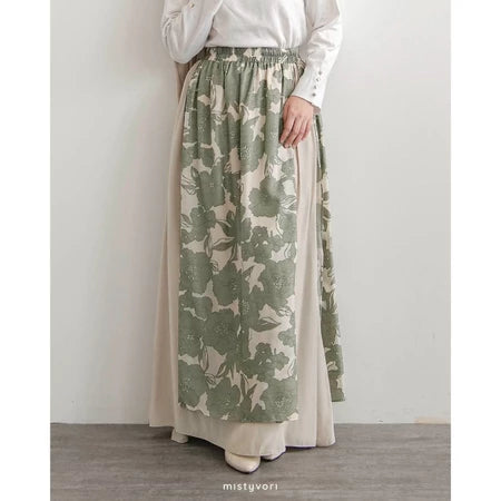 Person wearing a long green and beige patterned skirt by Mistyvori with a plain white top against a light gray background.