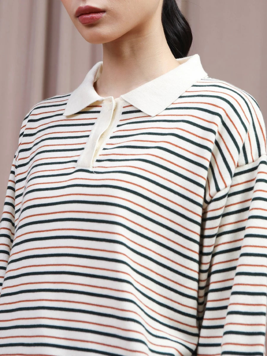 A close-up of a model wearing a long-sleeve polo shirt by Hijabchic with horizontal stripes in green, orange, and black on an off-white base, featuring a solid off-white collar.