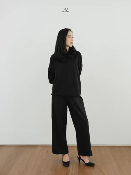 Woman wearing a black top and pants by Swifter against a white background