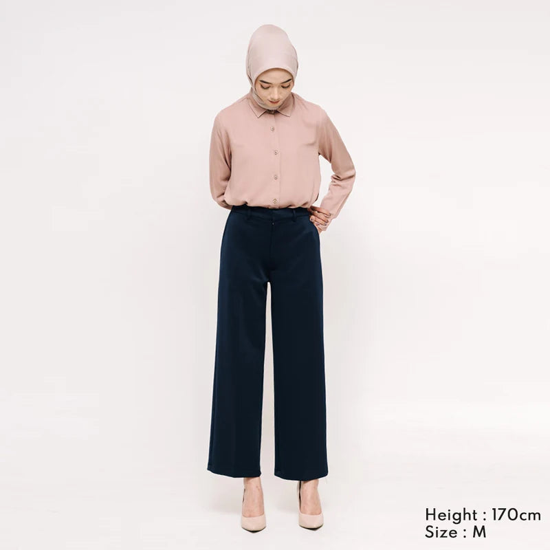 Woman wearing a light pink shirts and black culotte pants from Atala Scarves on a white background