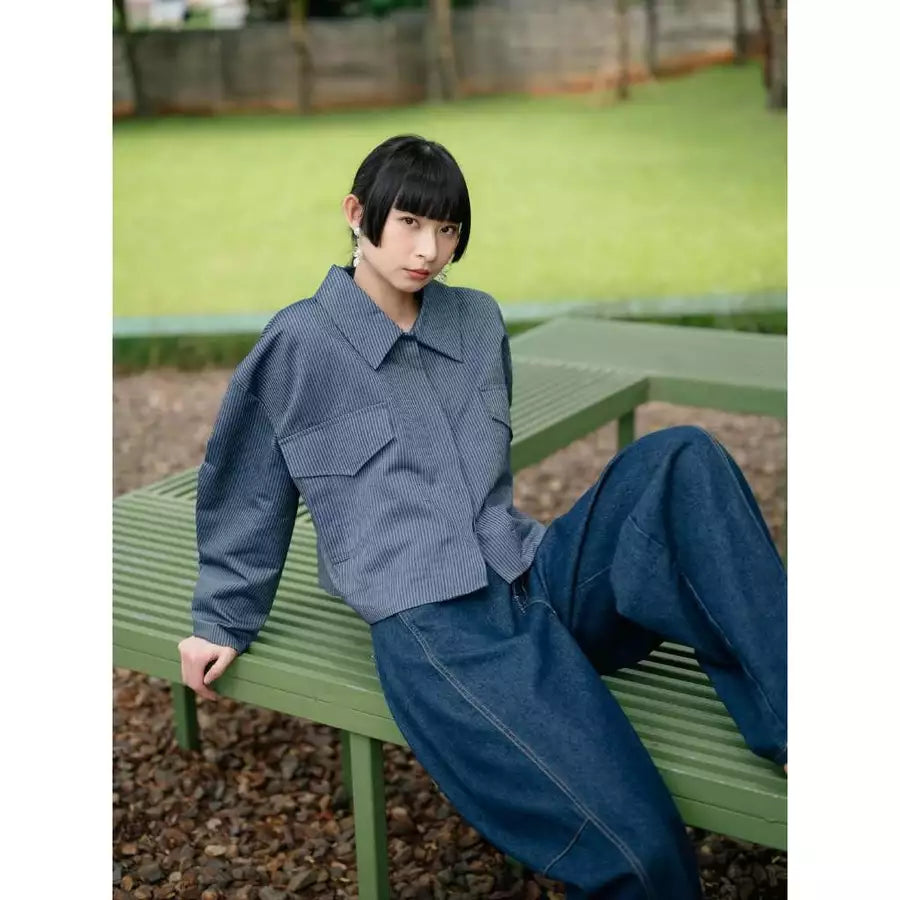 Person sitting on a green bench wearing a blue outer by Haidee Orlin with a blurred background