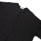 A close-up of a black textured button-up shirt by Yestoday with a stand collar, laid flat against a white background.