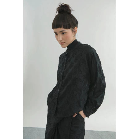 Person wearing a black textured shirt by Yestoday against a plain background