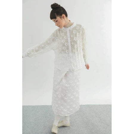 Person wearing a white floral shirt by Yestoday against a plain background